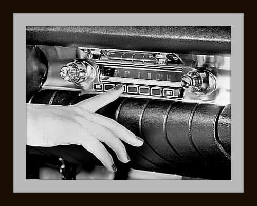 Close-up of a hand and vintage car radio in black and white